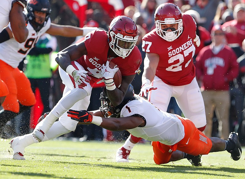 Oklahoma running back Trey Sermon (4) scramble to escape a tackle by Oklahoma State linebacker Calvin Bundage (1) in the first quarter of an NCAA college football game in Norman, Okla., Saturday, Nov. 10, 2018. (AP Photo/Alonzo Adams)