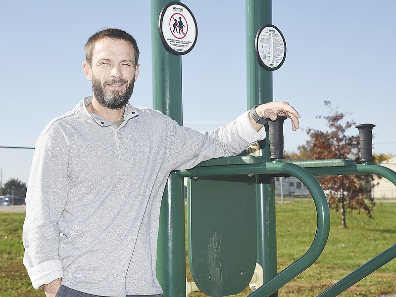 Justin Reynolds poses at a piece of workout equipment located on the waling track behind Callaway Hills Elementary School in Holts Summit.