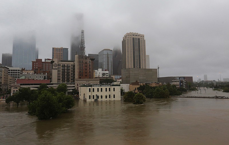 In this Monday, Aug. 28, 2017 file photo, floodwaters from Tropical Storm Harvey overflow from Buffalo Bayou in downtown Houston, Texas. A study released on Wednesday, Nov. 14, 2018 says that between being tripped up by downtown and the bigger effect of massive paving and building up of the metro area to reduce drainage, development in Houston on average increased the extreme flooding risk by 21 times. (AP Photo/LM Otero)