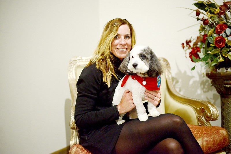 Capital City Court Appointed Special Advocates for children volunteer Lisa Bax holds Olive, CASA's therapy courtroom dog Wednesday during the CASA After Hours event at Turkey Creek Golf Complex.