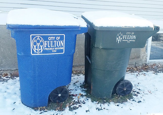 Familiar blue and green bins are shown in a Fulton yard, one for recycling and the other for normal garbage. Recycling costs are driving city officials to discuss options.