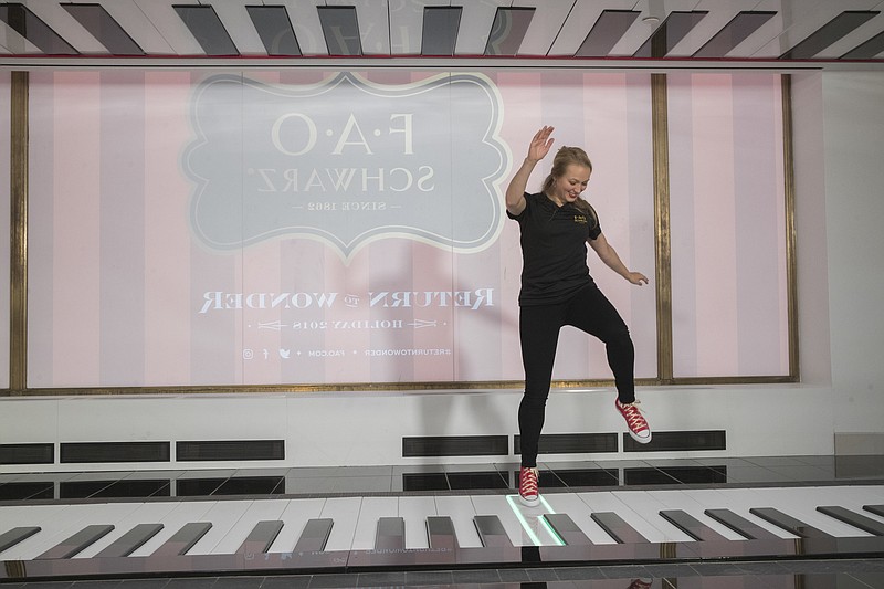 In this Tuesday, Nov. 13, 2018 photo, an employee plays the FAO Premium Piano Dance Mat during a media preview of the new FAO Schwarz store at Rockefeller Center in New York. Three years after it closed its beloved, fantasy land of a toy store on Fifth Avenue, FAO Schwarz makes its return to New York City. The new version will be smaller, but will have familiar attractions including a musical clock tower and the giant piano keyboard mat on which Tom Hanks danced in the film “Big.” (AP Photo/Mary Altaffer)