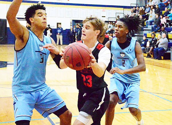 Jefferson City's Ben Folz drives the ball past Father Tolton's Coban Porter (left) and Nate Schwartze (right) during Thursday's Helias Jamboree at Rackers Fieldhouse.