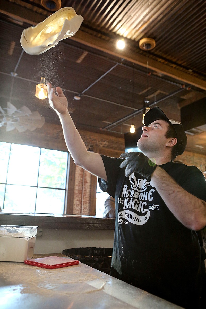 Pizza master Chase Porier tosses up fresh dough for pizza on Thursday at Redbone Magic Brewing Co. 