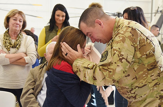 With family in the background looking on, Chief Warrant Officer 3 Matthew Sandbothe tries to console his 9-year-old daughter, Mattie Grace, as he prepares to board a plane Friday en route to transport to Kuwait for a nine-month deployment with his regiment. He's one of six from Detachment 2, Company C, 2nd-245th Aviation Regiment to serve the tour of duty, making this his third deployment.