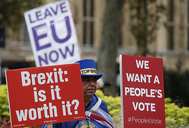 Pro and anti Brexit protesters hold placards as they vie for media attention near Parliament in London, Friday, Nov. 16, 2018.  Britain's Prime Minister May still faces the threat of a no-confidence vote, after several Conservative Party lawmakers said they had written letters asking for one. (AP Photo/Alastair Grant)