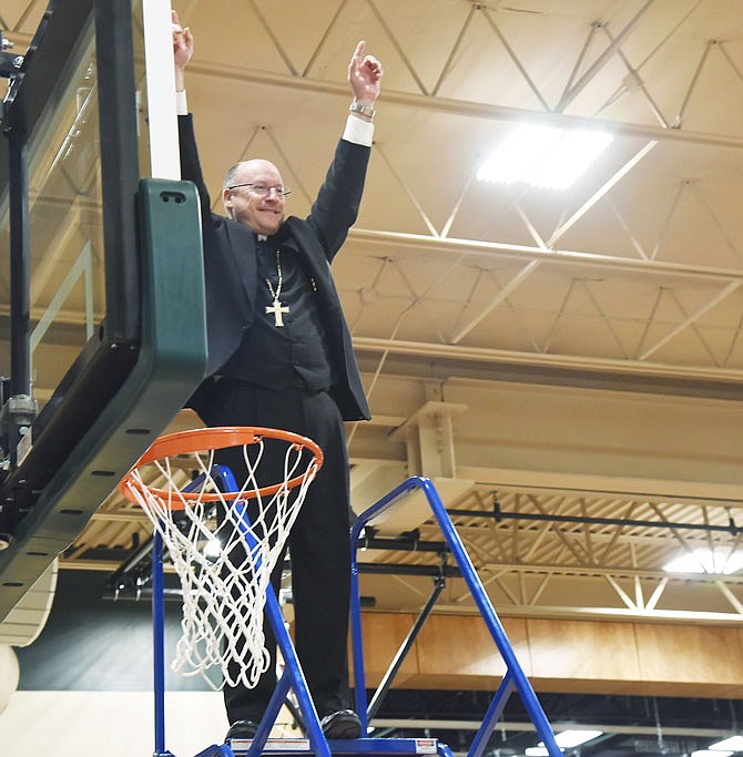 Bishop Shawn McKnight raises his hands in celebration after making the ceremonial first dunk in the basketball hoop. St. Joseph Cathedral School celebrated the completion of its new gym and performing arts center with a ribbon cutting and a blessing Friday morning. The Jefferson City Area Chamber of Commerce Ambassadors were on hand for the ceremony and handled the ribbon cutting.