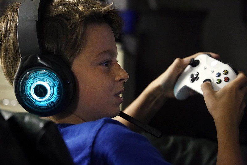 In this Saturday, Oct. 6, 2018, photo, Henry Hailey, 10, plays the online game Fortnite in the early morning hours in the basement of his Chicago home. His parents are on a quest to limit screen time for him and his brother. The boys say they understand sometimes, but also complain that they get less screen time than their friends. (AP Photo/Martha Irvine)