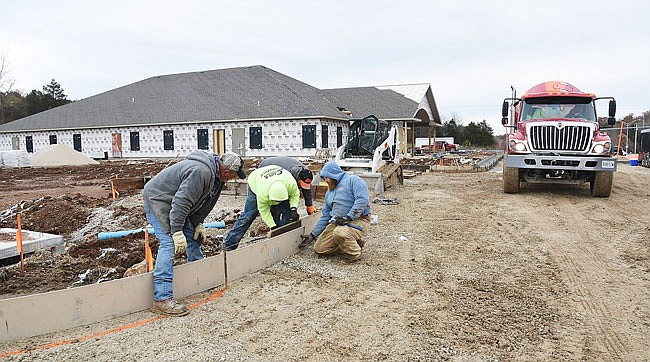 A Cole County Industries concrete truck rolls out of the driveway as a crew from Clift & Crawford Concrete Construction set forms in preparation for concrete curbing. The crew is, from left, Braxton Williamson, Brandon Cantrell, Bill Stark and Scott Crosser.