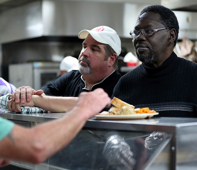  Mark Anthony Ward, right, with Ward Nation, and Scott Hebert, chef and kitchen manager at The Salvation Army's Center of 
Hope in Galveston, Texas, talk with clients Saturday as they serve dinner.