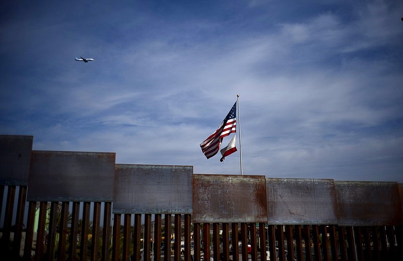 U.S. and California state flags fly behind the border wall, seen from Tijuana, Mexico, Monday, Nov. 19, 2018. Tensions have built as nearly 3,000 migrants from a caravan poured into Tijuana in recent days after more than a month on the road — and with many more months likely ahead of them while they seek asylum in the U.S. The federal government estimates the number of migrants could soon swell to 10,000.