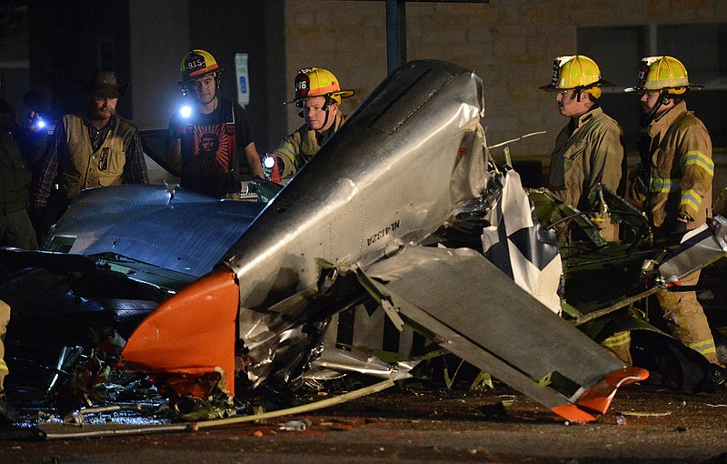 Firefighters and investigators look over a vintage World War II P-51D Mustang aircraft Saturday after a deadly crash in Fredericksburg, Texas.