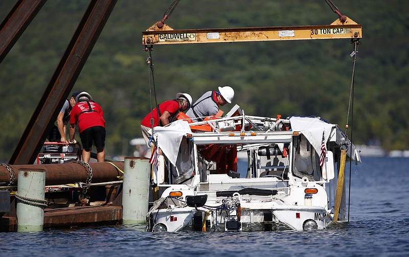 FILE- In this July 23, 2018, file photo the duck boat that sank on July 19 in Table Rock Lake in Branson, Mo., is raised. The company that owns the boat that sank, killing 17 people, has settled the first of several lawsuits filed in the accident. (Nathan Papes/The Springfield News-Leader via AP)