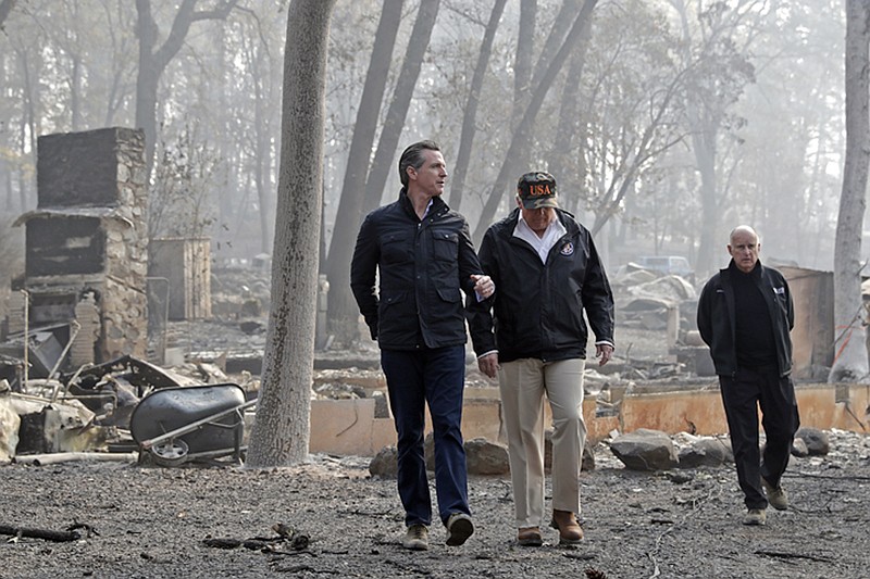 FILE - In this Nov. 17, 2018 file photo, President Donald Trump talks with from left, Gov.-elect Gavin Newsom, as California Gov. Jerry Brown, walks at right during a visit to a neighborhood destroyed by the Camp wildfire in Paradise, Calif. For US governors, including those taking office early next year, fires, floods and other climate-related emergencies could become top policy concerns. During his campaign, Newsom said the state needs to be more aggressive in clearing trees and brush, particularly its millions of dead trees. (AP Photo/Evan Vucci, File)