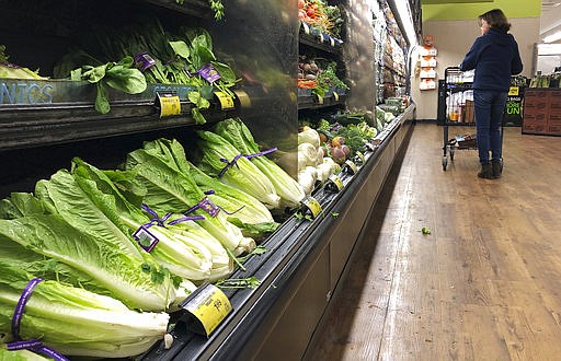 Romaine Lettuce still sits on the shelves as a shopper walks through the produce area of an Albertsons market Tuesday, Nov. 20, 2018, in Simi Valley, Calif. Health officials in the U.S. and Canada told people Tuesday to stop eating romaine lettuce because of a new E. coli outbreak. (AP Photo/Mark J. Terrill)