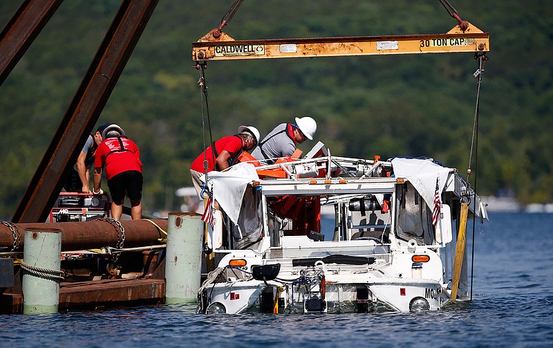 In this July 23, 2018, file photo the duck boat that sank on July 19 in Table Rock Lake in Branson, Mo., is raised. The company that owns the boat that sank, killing 17 people, has settled the first of several lawsuits filed in the accident. (Nathan Papes/The Springfield News-Leader via AP)