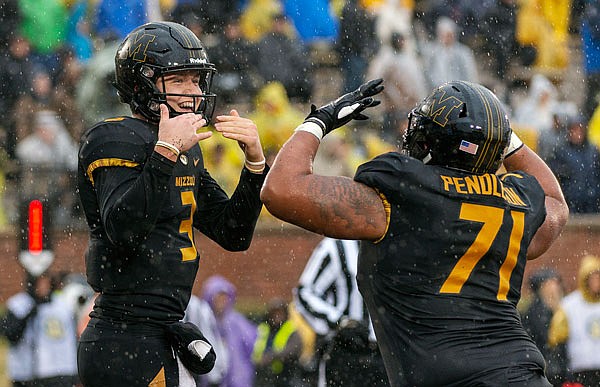 Missouri quarterback Drew Lock celebrates in the rain with offensive lineman Kevin Pendleton after rushing for a touchdown during Friday afternoon's game against Arkansas at Faurot Field.