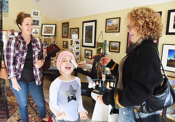 Layla Andrews, 5, reacts to her grandmother, Theresa Roedel, at right, pulling the headband over her head at The Art Bazaar on Jefferson City's east side. The local artist co-op was one of several area businesses to participate in the annual Small Business Saturday shopping day.
