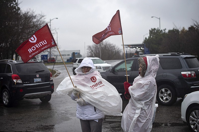 Members of Unifor, the union representing the workers of Oshawa's General Motors assembly plant, stand near the entrance to the plant in Oshawa, Ontario, Monday, Nov. 26, 2018. General Motors will lay off thousands of factory and white-collar workers in North America and put five plants up for possible closure as it restructures to cut costs and focus more on autonomous and electric vehicles. General Motors is closing the Oshawa plant. (Eduardo Lima/The Canadian Press via AP)