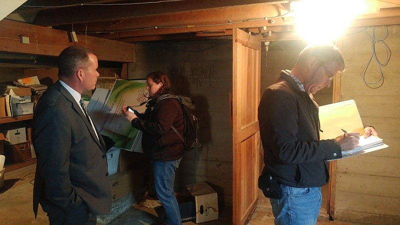 <p>Blair Oaks R-2 Superintendent Jim Jones (at left) spends some time with engineers Victoria Winn (center) and Michael Griffin (right) as they start visual seismic inspections of the school district’s buildings Wednesday with the former house that is Blair Oaks’ central office. The group is pictured standing in the basement of the office.</p>