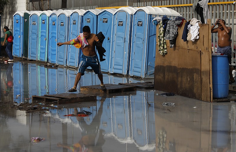 Migrants use a flooded shower and toilet area at a sports complex sheltering thousands of Central American migrants in Tijuana, Mexico, Thursday, Nov. 29, 2018. Aid workers and humanitarian organizations expressed concerns Thursday about the unsanitary conditions at the sports complex in Tijuana where more than 6,000 Central American migrants are packed into a space adequate for half that many people and where lice infestations and respiratory infections are rampant. (AP Photo/Rebecca Blackwell)