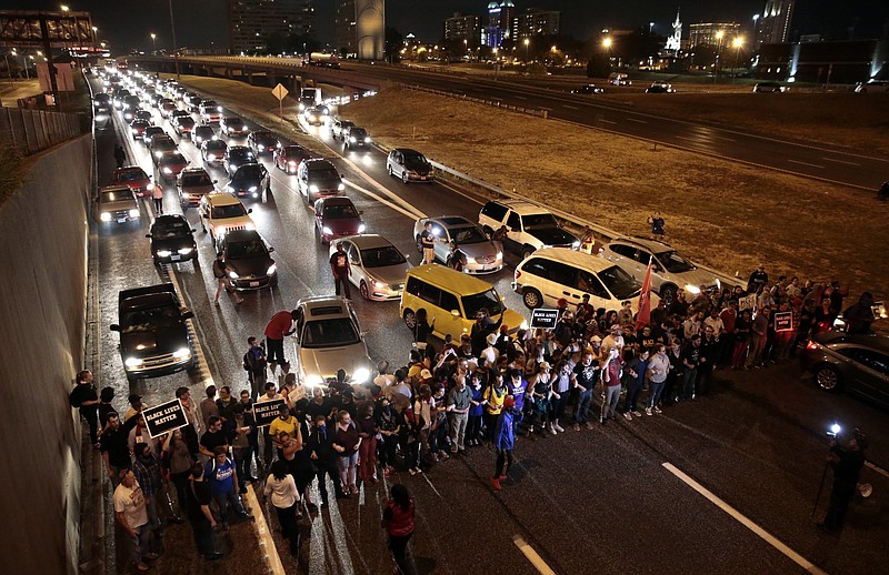 FILE - In this Oct. 3, 2017, file photo, protesters stop traffic on Interstate 64 (Highway 40) eastbound at the Compton Avenue overpass in St. Louis, as part of ongoing demonstrations against the acquittal of a white former police officer in the 2011 killing of a black man. Three St. Louis police officers were indicted Thursday, Nov. 29, 2018, for allegedly beating an undercover colleague during a 2017 protest and, along with a fourth officer, conspiring to cover up the crime. (Robert Cohen/St. Louis Post-Dispatch via AP, File)