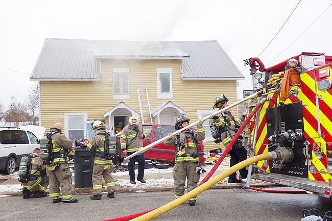 Members of the Fulton Fire Department prepare to enter a duplex on East 6th Street that caught on fire Wednesday. The fire was confined to the attic, though lower levels received water damage, Fulton Fire Chief Kevin Coffelt said.