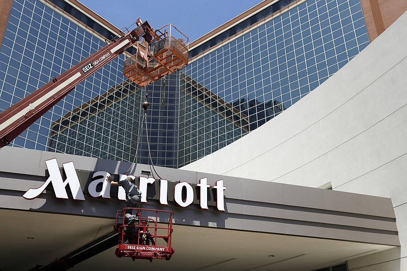 FILE - In this Tuesday, April 30, 2013, file photo, a man works on a new Marriott sign in front of the former Peabody Hotel in Little Rock, Ark.  Marriott says the information of up to 500 million guests at its Starwood hotels has been compromised. It said Friday, Nov. 30, 2018,  that there was a breach of its database in September, but also found out through an investigation that there has been unauthorized access to the Starwood network since 2014.(AP Photo/Danny Johnston, File)