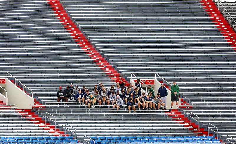 Members of the Little Rock Christian Academy football team watch and wait to practice at War Memorial Stadium in Little Rock Thursday morning. Little Rock Christian was scheduled to play Pulaski Academy tonight in the 5A championship game, but the game was moved to Sunday because of the threat of severe storms.