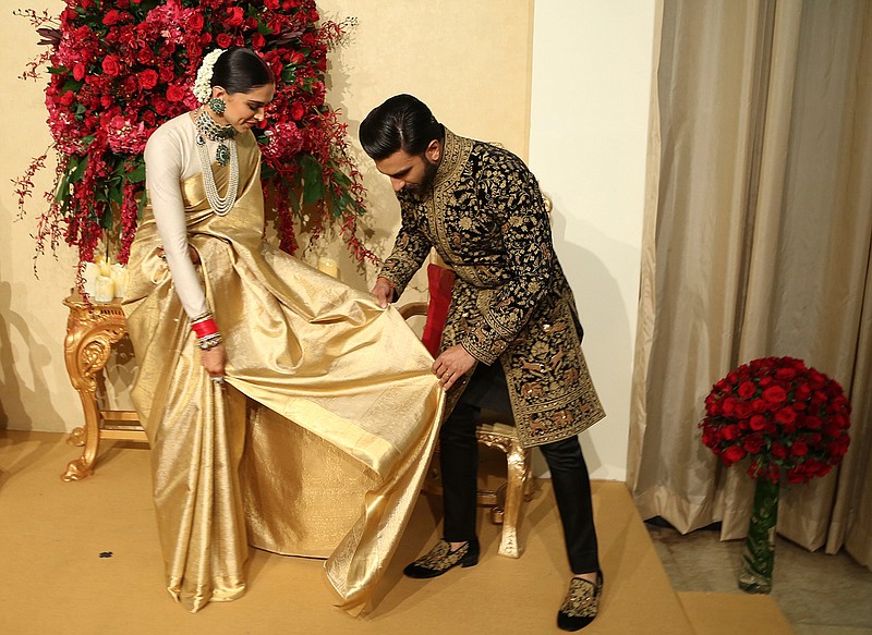 Bollywood actor Ranveer Singh, right, helps his wife Deepika Padukone adjust her attire as they pose at their wedding reception in Bangalore, India, Wednesday, Nov. 21, 2018. The couple got married at Villa Balbianello, a lakeside mansion featured in Star Wars and James Bond films in Lenno, Como lake, northern Italy on Nov. 14, 2018. (AP Photo/Aijaz Rahi)