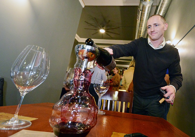 Mark Wilson/News TribuneMatt Green, owner of Bar Vino, pours a bottle of wine during a soft opening event held Wednesday evening. Bar Vino is a new wine bar on High Street that will officially open on Dec. 3. 