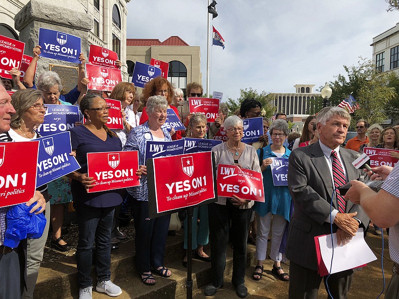 FILE - In this Aug. 31, 2018 file photo, supporters of Missouri's redistricting ballot measure hold signs behind former state Sen. Bob Johnson as he serves as their spokesman during a press conference outside the Cole County Courthouse in Jefferson City, Mo. Voters approved Constitutional Amendment 1 on the Nov. 6 ballot. It is unique among redistricting reforms adopted by a number of states in recent years because it requires Missouri's state legislative districts to be drawn using a new mathematical formula to try to achieve "partisan fairness" and "competitiveness" after the 2020 Census. (AP Photo/David A. Lieb, File)