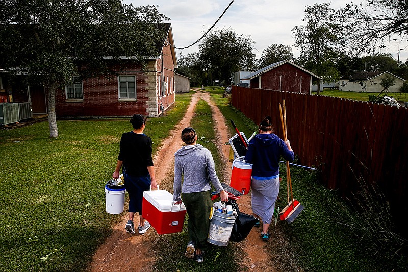 Amish volunteers with the Mennonite Disaster Service carry cleaning supplies down a road after finishing building a home for a man who lost his house to Hurricane Harvey Tuesday, Nov. 13, 2018, in Bloomington, Texas.(Michael Ciaglo/Houston Chronicle via AP)