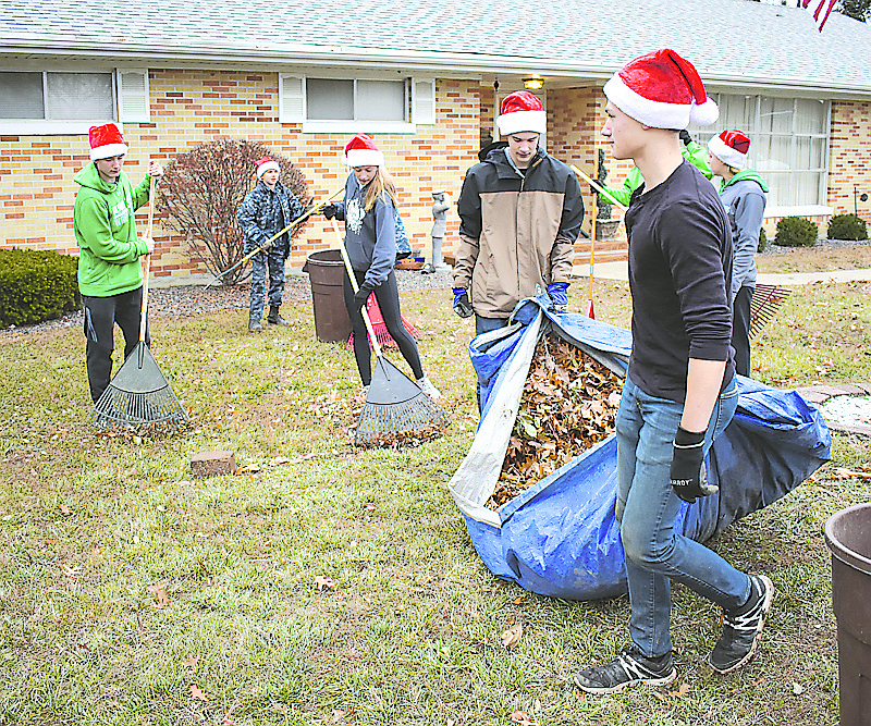 In the foreground, brothers Adam, left, and Philip Crawford carry a tarp full of leaves from Mary Lou Scott's yard during the final day of Leaf Relief. The fundraiser supports Operation Bugle Boy.