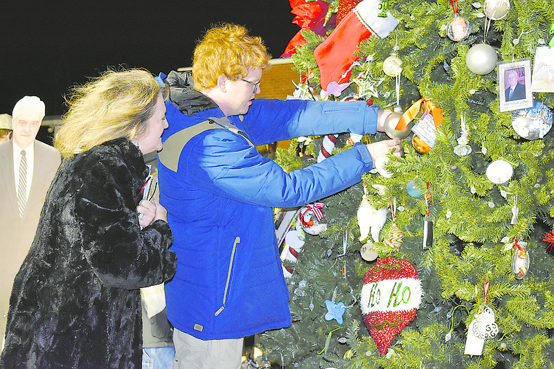 With a life-size cutout of Jack Steppleman on the left, Steppleman's grandson Branden Biggs places an ornament on Jack's Memory Tree Sunday at Houser-Millard Family Chapels. Biggs' mother, Stephanie Biggs, one of Steppleman's two daughters, looks on.