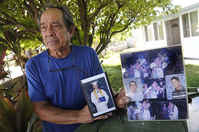 FILE - In this July 10, 2017, file photo, Clifford Kang, father of soldier Ikaika E. Kang, poses with photos of his son in Kailua, Hawaii. Ikaika E. Kang, an active-duty U.S. soldier, arrested on terrorism charges that accuse him of pledging allegiance to the Islamic State group, is scheduled to be sentenced, Tuesday, Dec. 4, 2018. (Bruce Asato/Honolulu Star-Advertiser via AP, File)