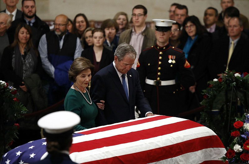 Former President George W. Bush and former first lady Laura Bush pause in front of the flag-draped casket of former President George H.W. Bush as he lies in state in the Capitol's Rotunda in Washington, Tuesday, Dec. 4, 2018. (AP Photo/Patrick Semansky)