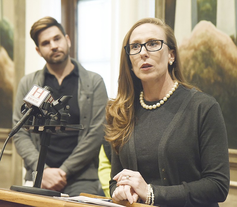 Missouri HIV Justice Coalition member Brennan Keiser, background, listens as Rep. Holly Rehder, R-Sikeston, answers questions from the media Monday during a press conference in the House of Representatives Lounge.