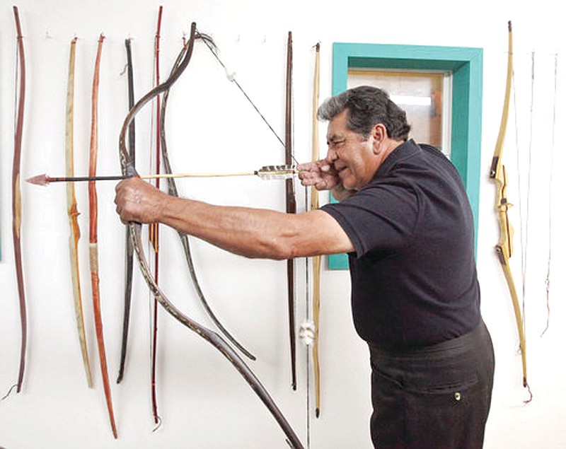 Joe Hernandez demonstrates the pull on a bow made of old sage on Oct. 24 at his workshop in Odessa, Texas.