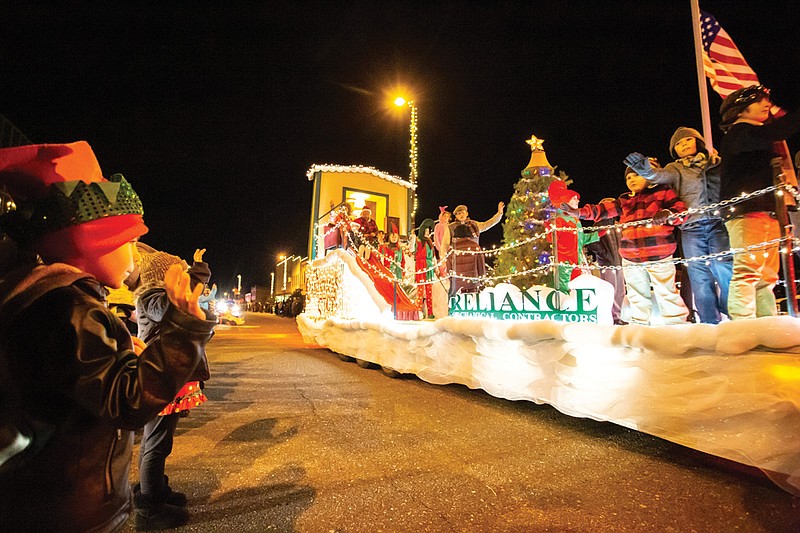 The crowd waves to children on a float Monday evening during the annual Christmas Parade in downtown Texarkana.