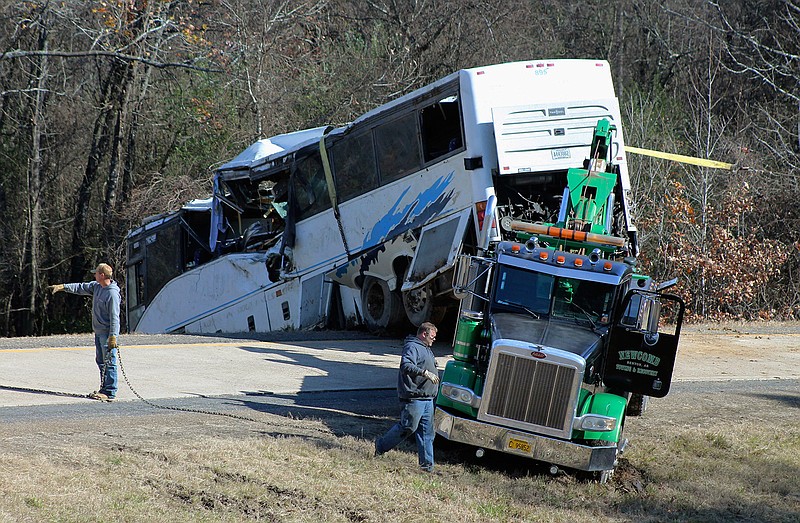 Employees from a wrecker service work to remove a charter bus from a roadside ditch Monday, Dec. 3, 2018, after it crashed alongside Interstate 30 near Benton, Ark. The bus was carrying a youth football team from Tennessee when it rolled off an interstate off-ramp and overturned before sunrise Monday. The elementary-school age football team from Orange Mound Youth Association in southeast Memphis had played in a tournament in Dallas over the weekend. (Josh Briggs/Saline Courier via AP)