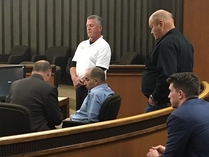 Tonny Ezernack, center, sits with hands cuffed behind his back as his lawyer, Butch Dunbar, speaks with him as Bowie County deputies stand nearby. Ezernack cursed at a prosecutor and disrupted closing remarks in the trial with verbal outbursts. 