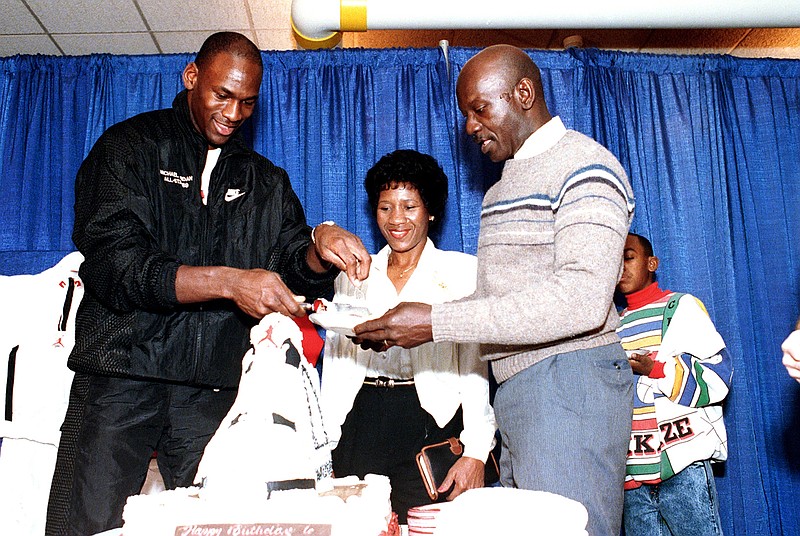 In this Feb. 17, 1989 file photo, Chicago Bulls' Michael Jordan serves his father, James, a slice of birthday cake as his mother, Doloris, watches during a party in honor of Jordan's 26th birthday in Chicago, Ill. James Jordan was killed July 23, 1993, and his body was found 11 days later in a South Carolina swamp. A North Carolina judge is scheduled to hear arguments Wednesday, Dec. 5, 2018, in the case of Daniel Green, who was identified as the triggerman in the 1993 death of James Jordan. (AP Photo/Charles Bennett, File)