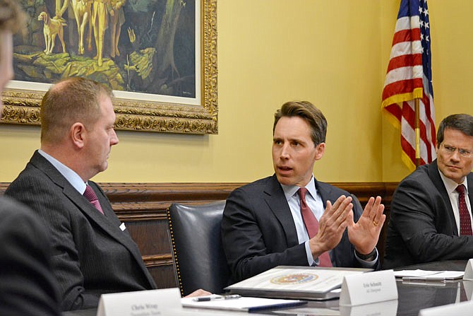 This Dec. 6, 2018 photo, Missouri Attorney General Josh Hawley, center, briefs incoming Attorney General Eric Schmitt, left, during a meeting in the Attorney General's office in the Supreme Court Building. Schmitt was named to take over the role in January because Hawley heads to Washington, D.C., as a U.S. Senator for Missouri.