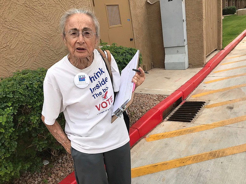 In this April 19, 2018 file photo, Rivko Knox, a volunteer with the League of Women Voters, collects signatures for a campaign financing ballot measure outside a polling station in Glendale, Ariz. A judge on Friday, Aug. 24, 2018 upheld a 2016 Arizona law that bans groups from collecting early mail-in ballots from voters and delivering them. The ruling dismissed a legal challenge to the law filed by Knox. (AP Photo/Anita Snow, File)