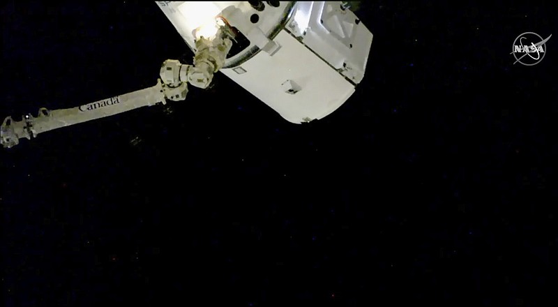In this image taken from NASA Television, the SpaceX Dragon cargo spacecraft is captured by a robotic arm for docking to the International Space Station, Saturday, Dec. 8, 2018. A SpaceX delivery full of  Christmas goodies has arrived at the International Space Station. The Dragon capsule pulled up at the orbiting lab Saturday, three days after launching from Florida. (NASA TV via AP)