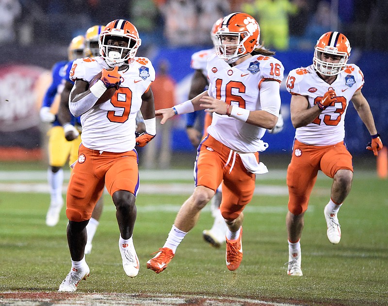 In this Saturday, Dec. 1, 2018, file photo, Clemson's Travis Etienne (9) followed by quarterback Trevor Lawrence (16) runs for a touchdown against Pittsburgh in the first half of the Atlantic Coast Conference championship NCAA college football game in Charlotte, N.C. Clemson's high-octane offense is led by the pair of young, talented offensive players. (AP Photo/Mike McCarn, File)