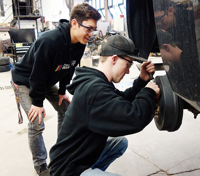 Ryu Taggart, left, watches as Cody Jaegers works Thursday to replace a break rotor on a pickup truck at the Nichols Career Center.