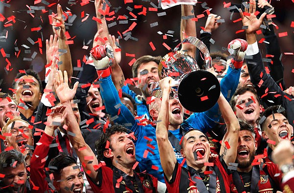 Atlanta United defender Michael Parkhurst (center left) and midfielder Miguel Almiron (center right) hoist the trophy as they celebrate defeating the Portland Timbers 2-0 to win the MLS Cup on Saturday in Atlanta.