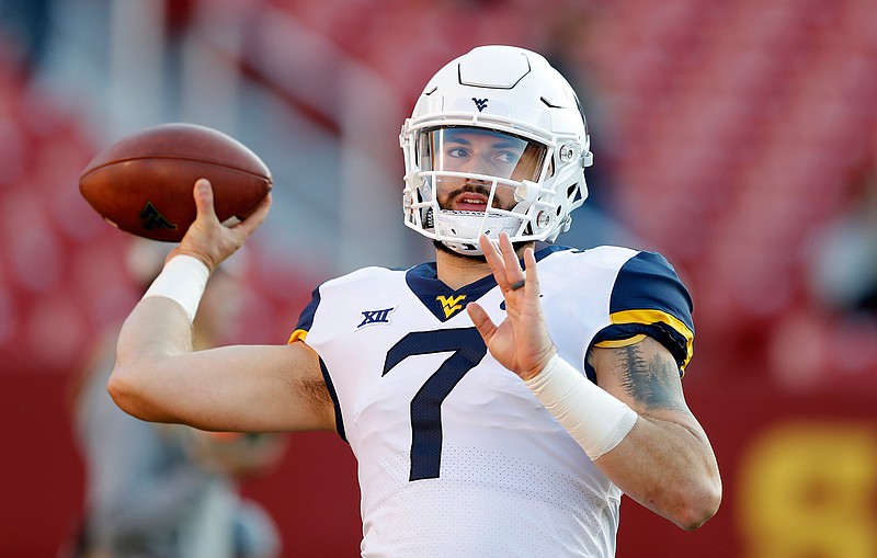 In this Saturday, Oct. 13, 2018 file photo, West Virginia quarterback Will Grier warms up before an NCAA college football game against Iowa State in Ames, Iowa. No. 6 West Virginia and No. 12 Oklahoma meet Friday night in Morgantown, W.Va., with the winner earning a berth in the Big 12 championship game next week. (AP Photo/Charlie Neibergall, File)